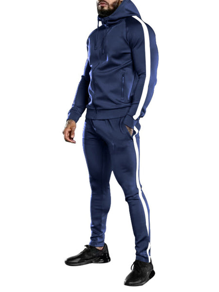 Man wearing navy blue tracksuit with white stripes, featuring hoodie and jogger pants, matched with black sneakers suitable for casual wear.